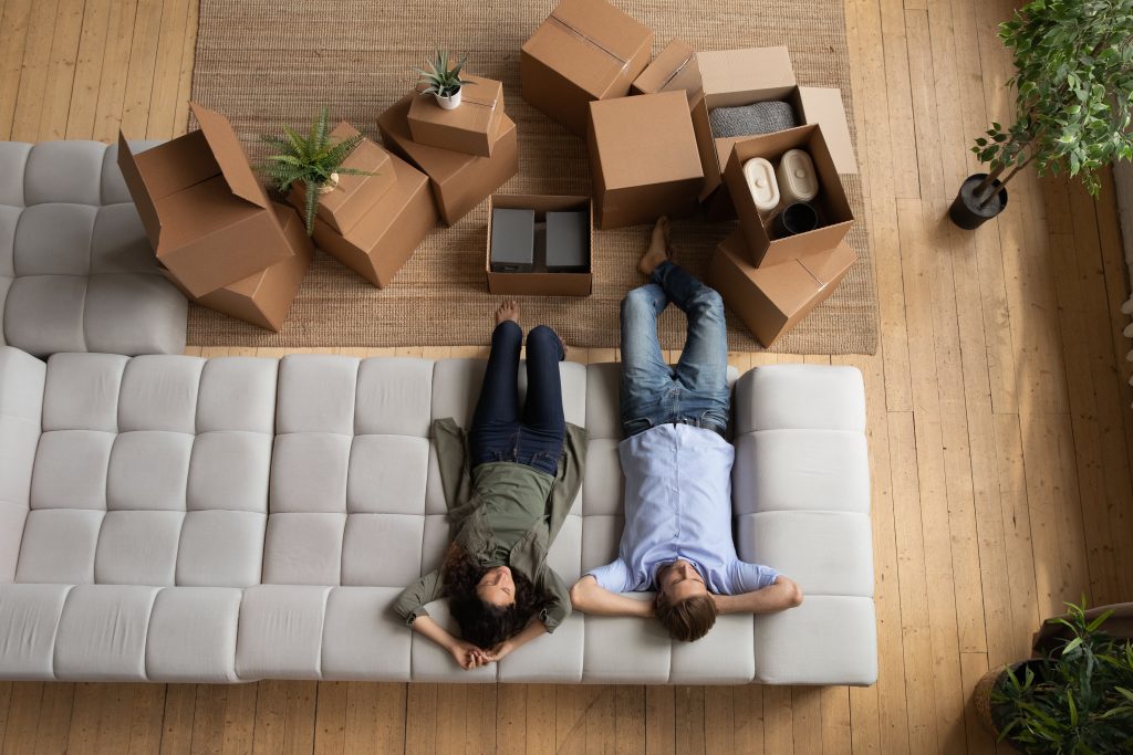 Overhead view of a couple relaxing on a couch after packing for a move
