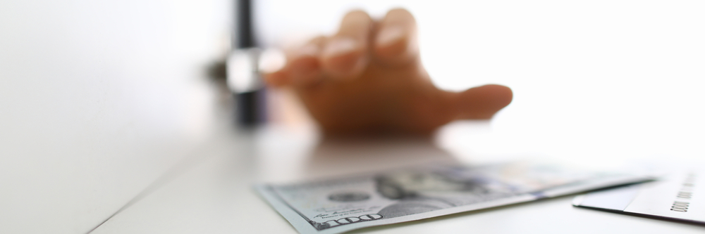 Hand reaching for $100 bill cash deposit