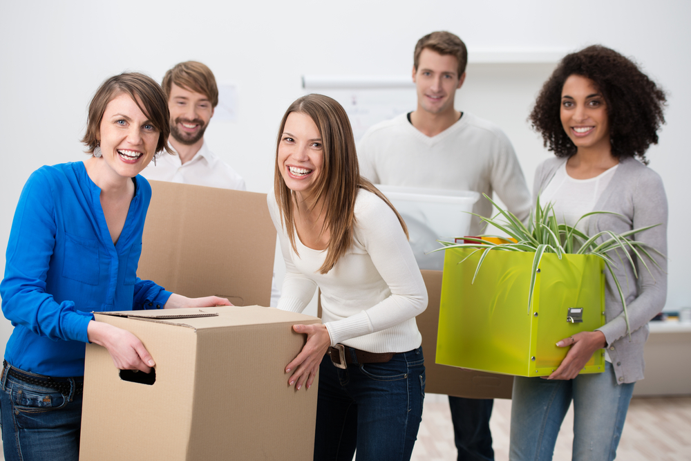 Smiling team members with boxes in an office